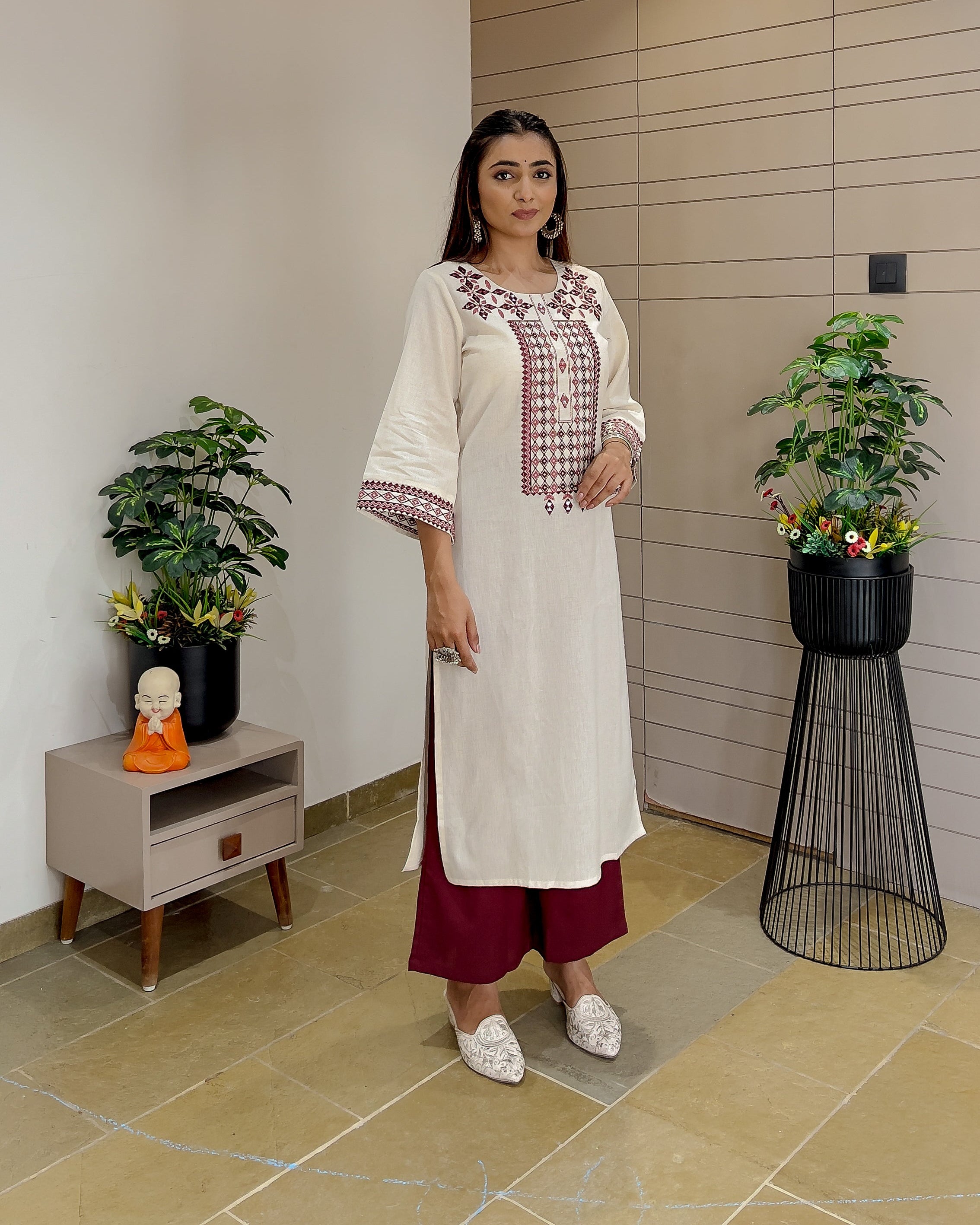 kurta with red pants standing in a modern interior setting.