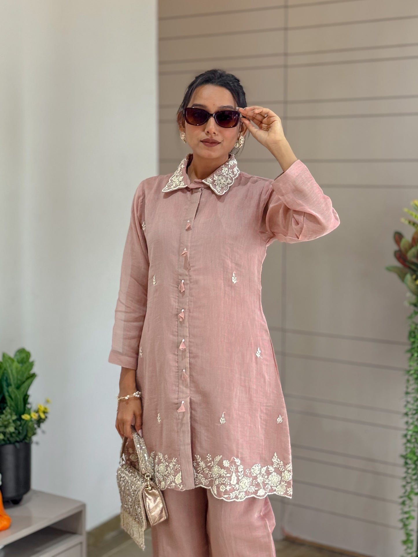 Woman wearing a dusty rose pink outfit with lace details indoors.