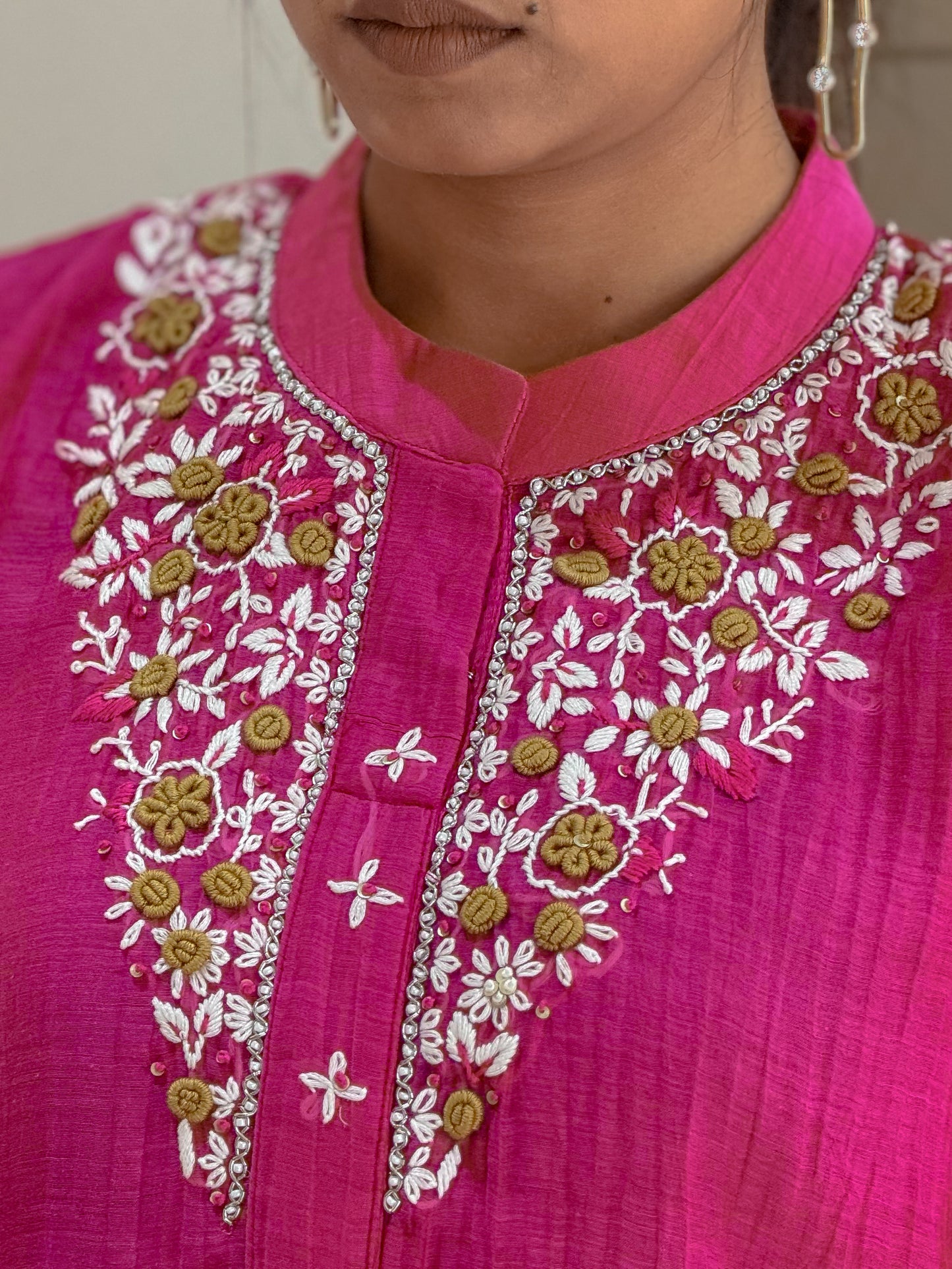 Close-up of a pink hand work garment with white and yellow details.