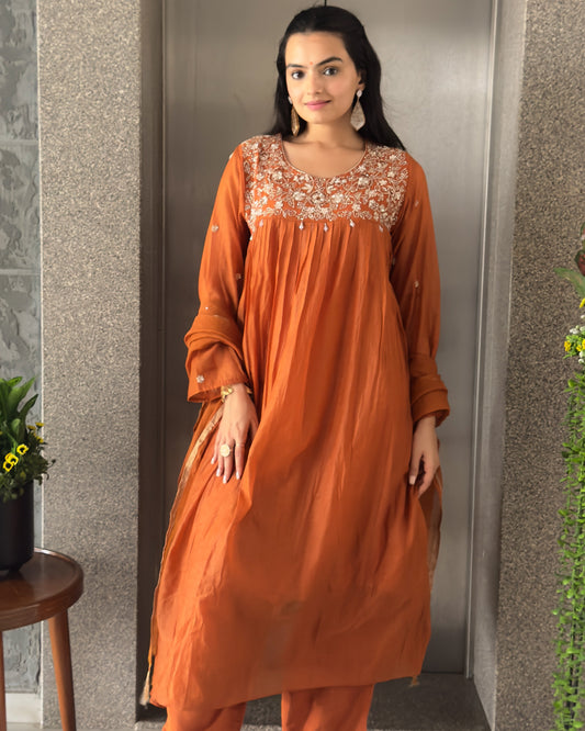 Woman in an orange traditional outfit standing.