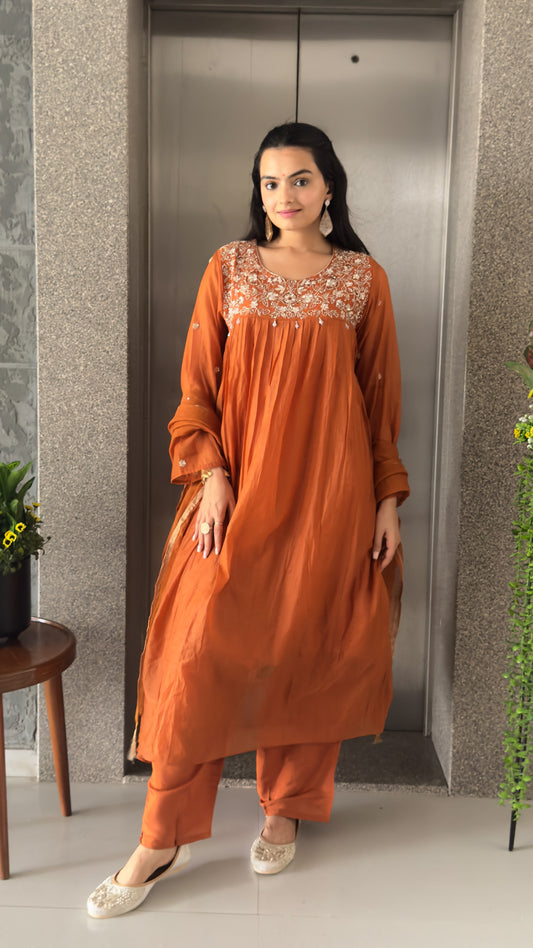 Woman in an orange traditional outfit standing.