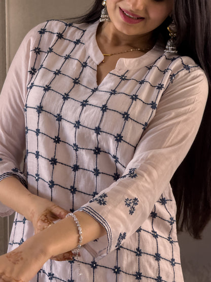 Woman wearing a white kurta with blue embroidery work.