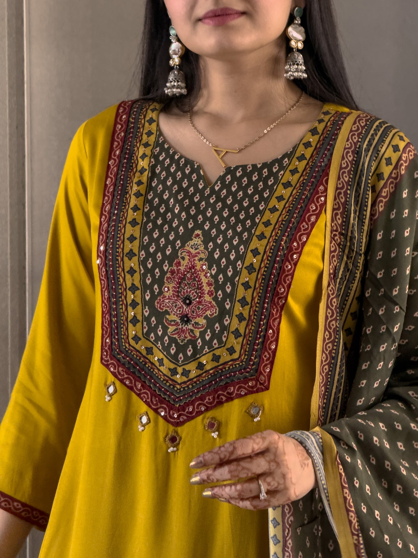 Woman wearing a yellow and brown embroidered traditional outfit.