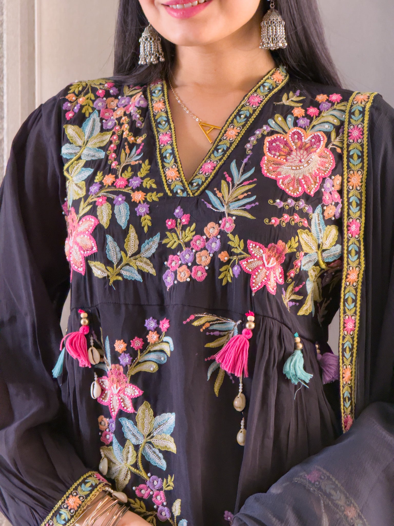 Woman wearing a black embroidered dress with colorful floral patterns.