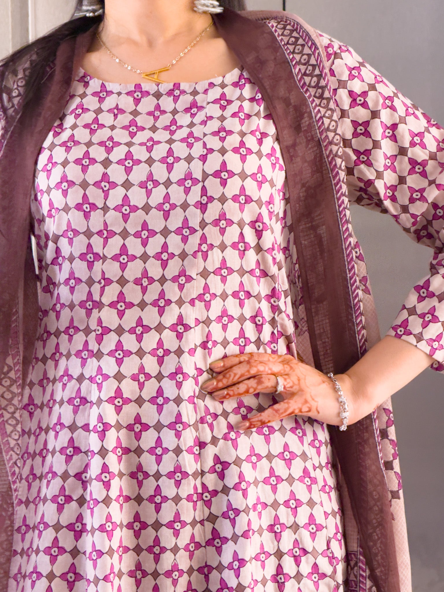Woman wearing a patterned dress with a brown shawl over .