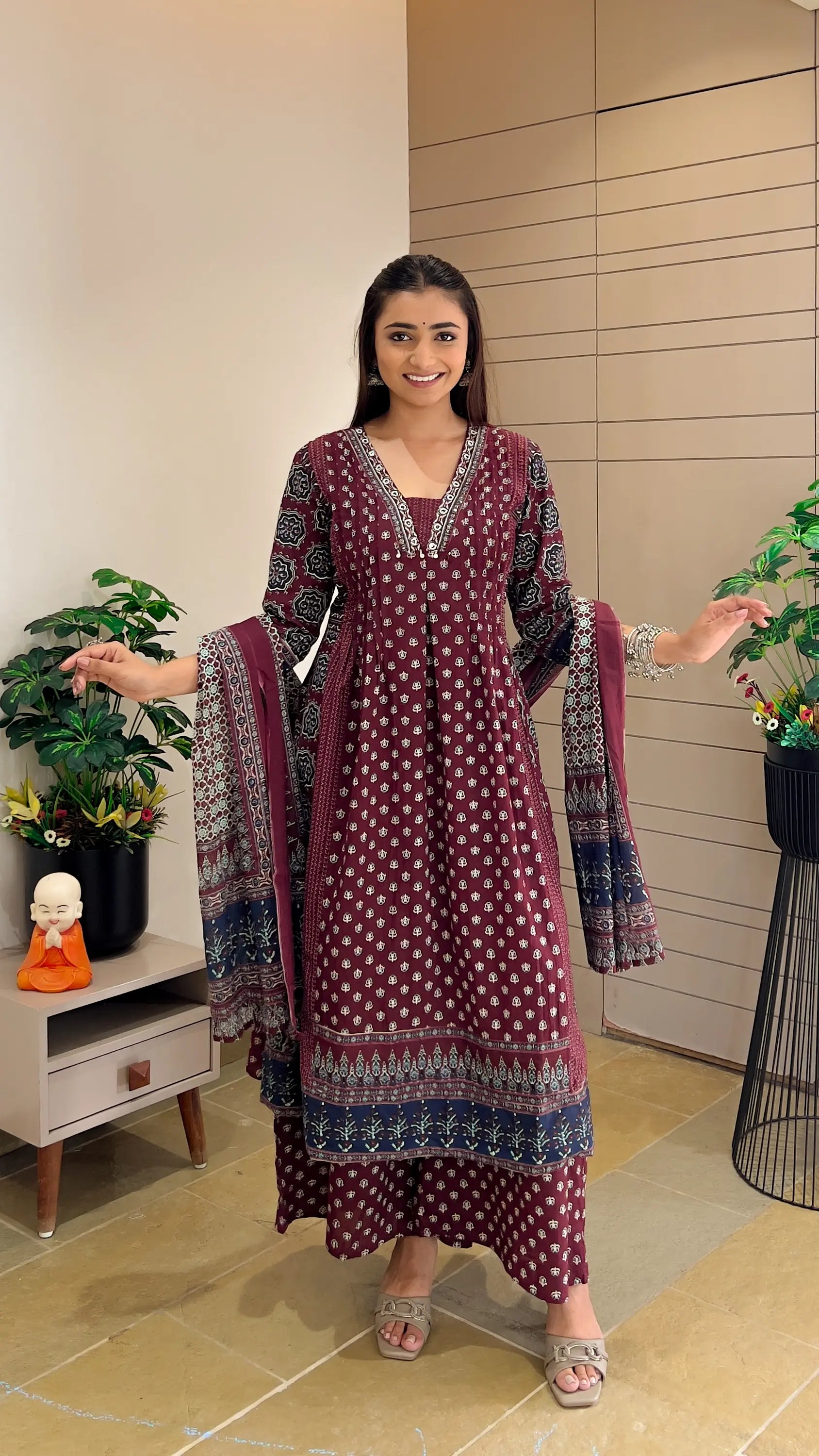 Woman wearing a maroon printed A-line kurta with matching palazzo pants and dupatta.